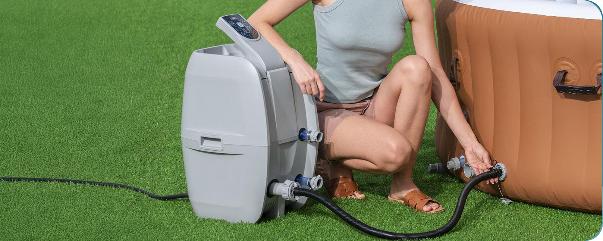 Close-up of a woman kneeling to connect a SaluSpa hot tub heater pump to a SaluSpa inflatable hot tub. 