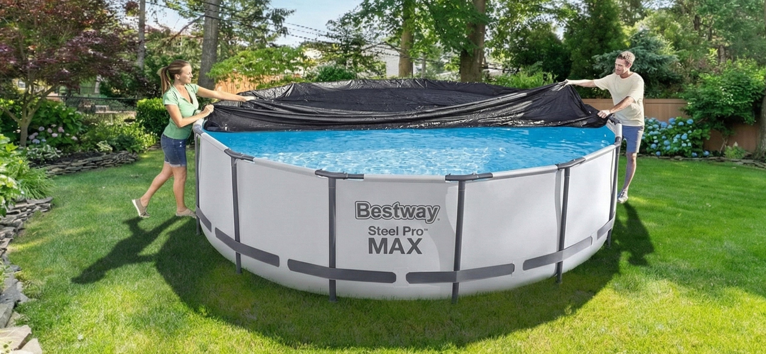 A woman and man are putting a pool cover on a Bestway Steel Pro MAX above ground pool. Trees in the background. 