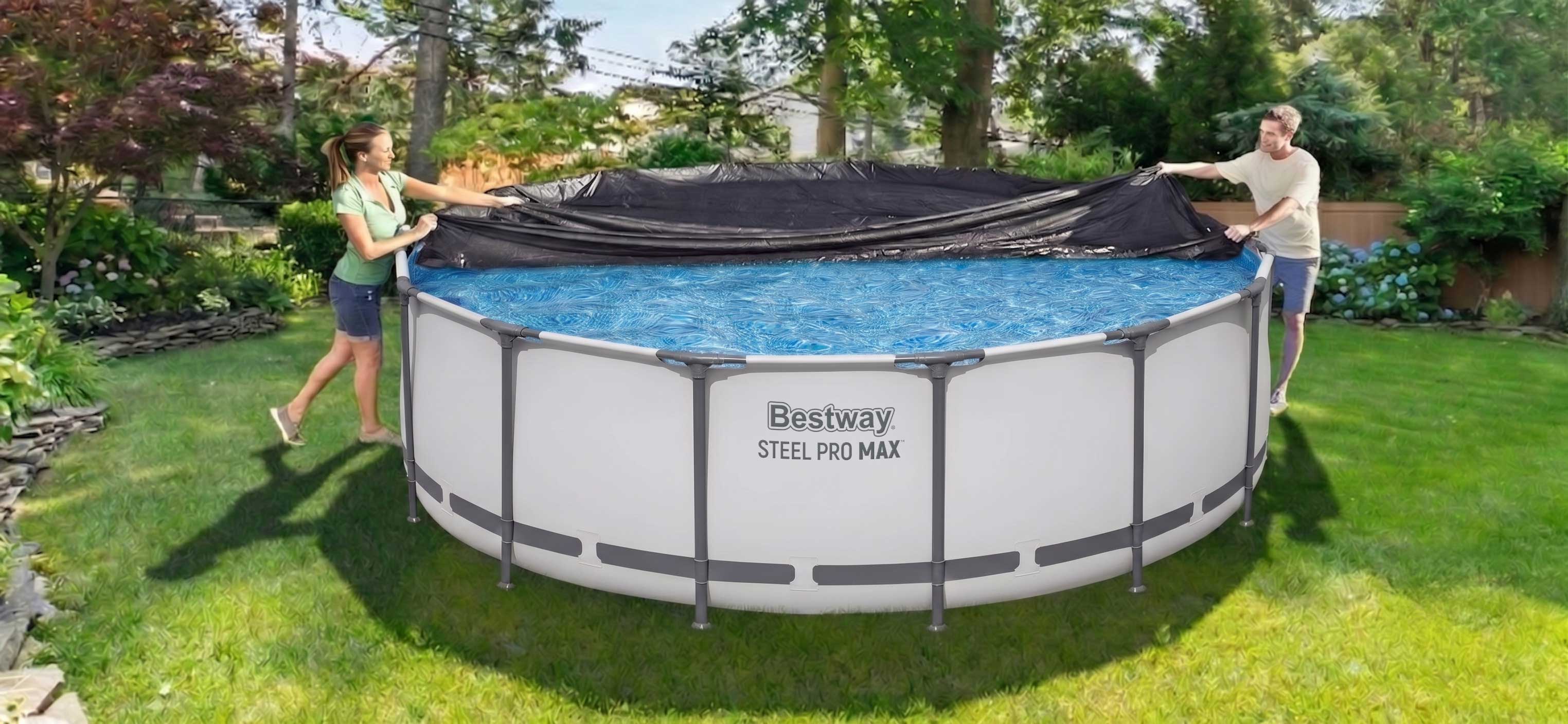 A woman and man are putting a pool cover on a Bestway Steel Pro MAX above ground pool. Trees in the background. 